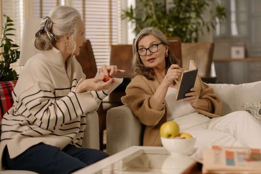 Two senior women having a warm and intimate conversation on a cozy couch indoors